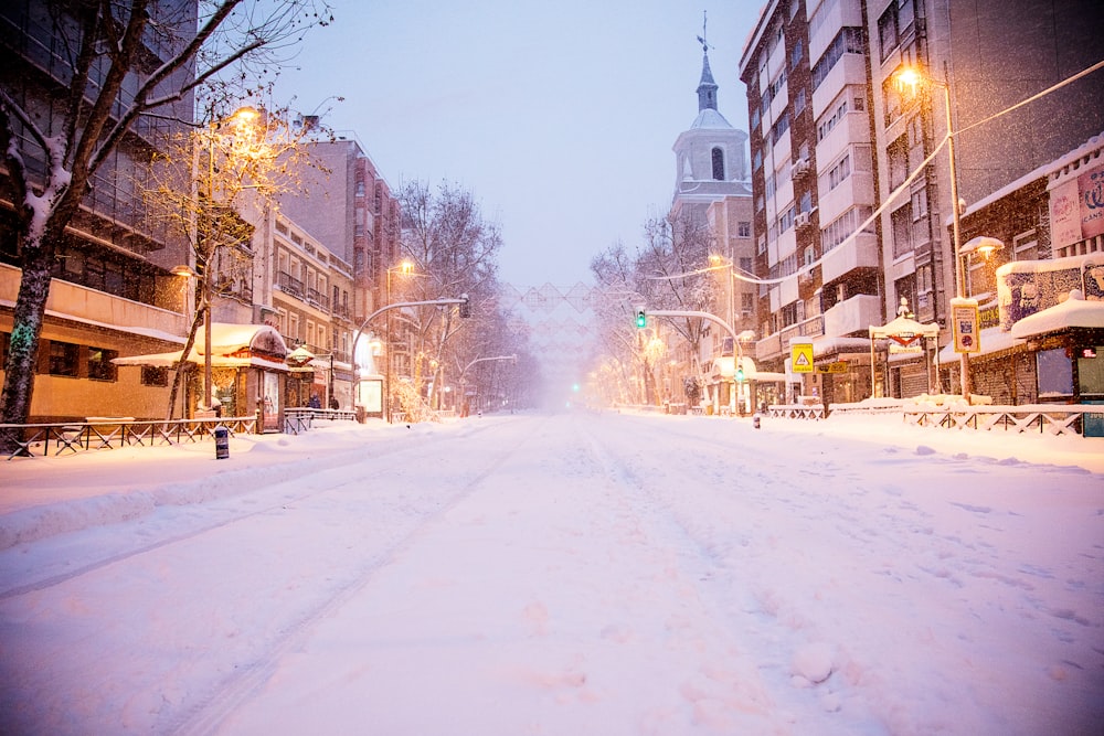 snow covered road between buildings during daytime