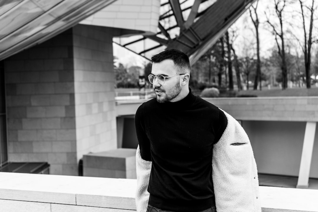 man in black crew neck long sleeve shirt and gray pants standing near building,