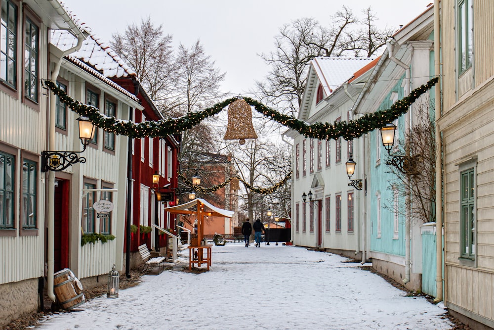 people walking on snow covered pathway between houses during daytime