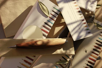 Close-up of a handcrafted wooden pen resting on a rustic wooden table with tropical foliage in the background.