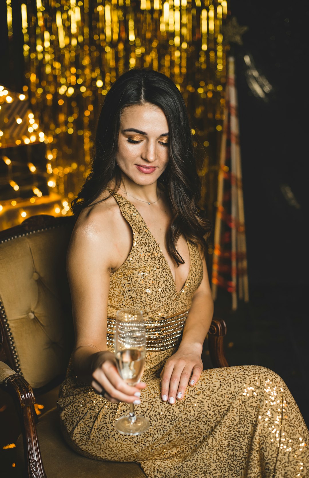 woman in gold sleeveless dress sitting on brown chair