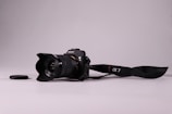 A DSLR camera with a lens resting on a wooden table.