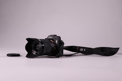 A DSLR camera with a lens resting on a wooden table.