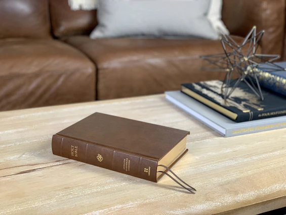 Cozy reading nook with open Bible and classic theological books on a wooden table.