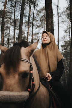 An elegant photoshoot featuring a Muslim female rider showcasing premium riding apparel with her horse.