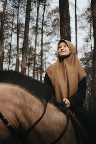 A Muslim female equestrian influencer in modest riding attire showcasing a luxury saddle brand.