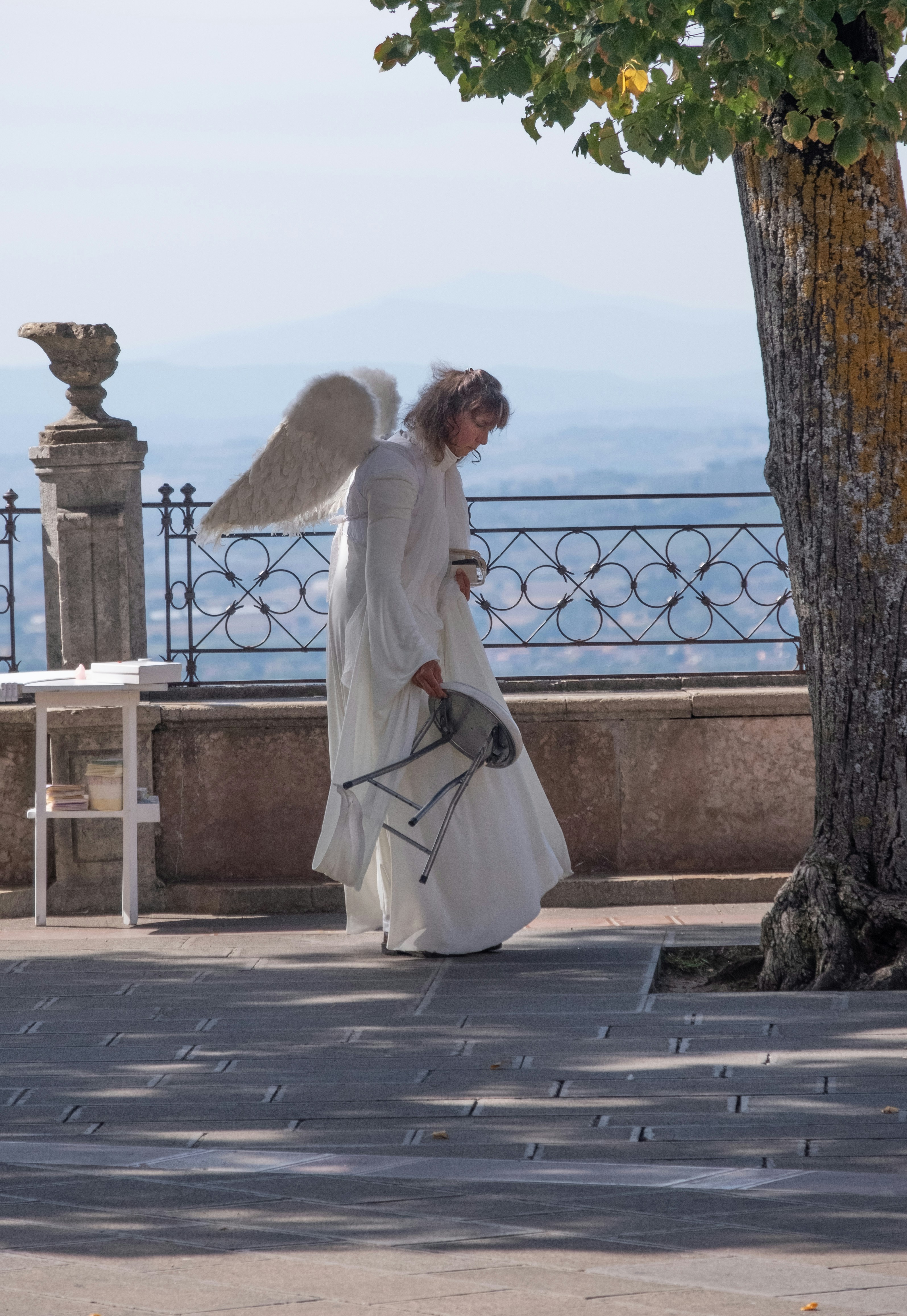 Femme en robe blanche à manches longues debout à côté d’une clôture en métal gris pendant la journée