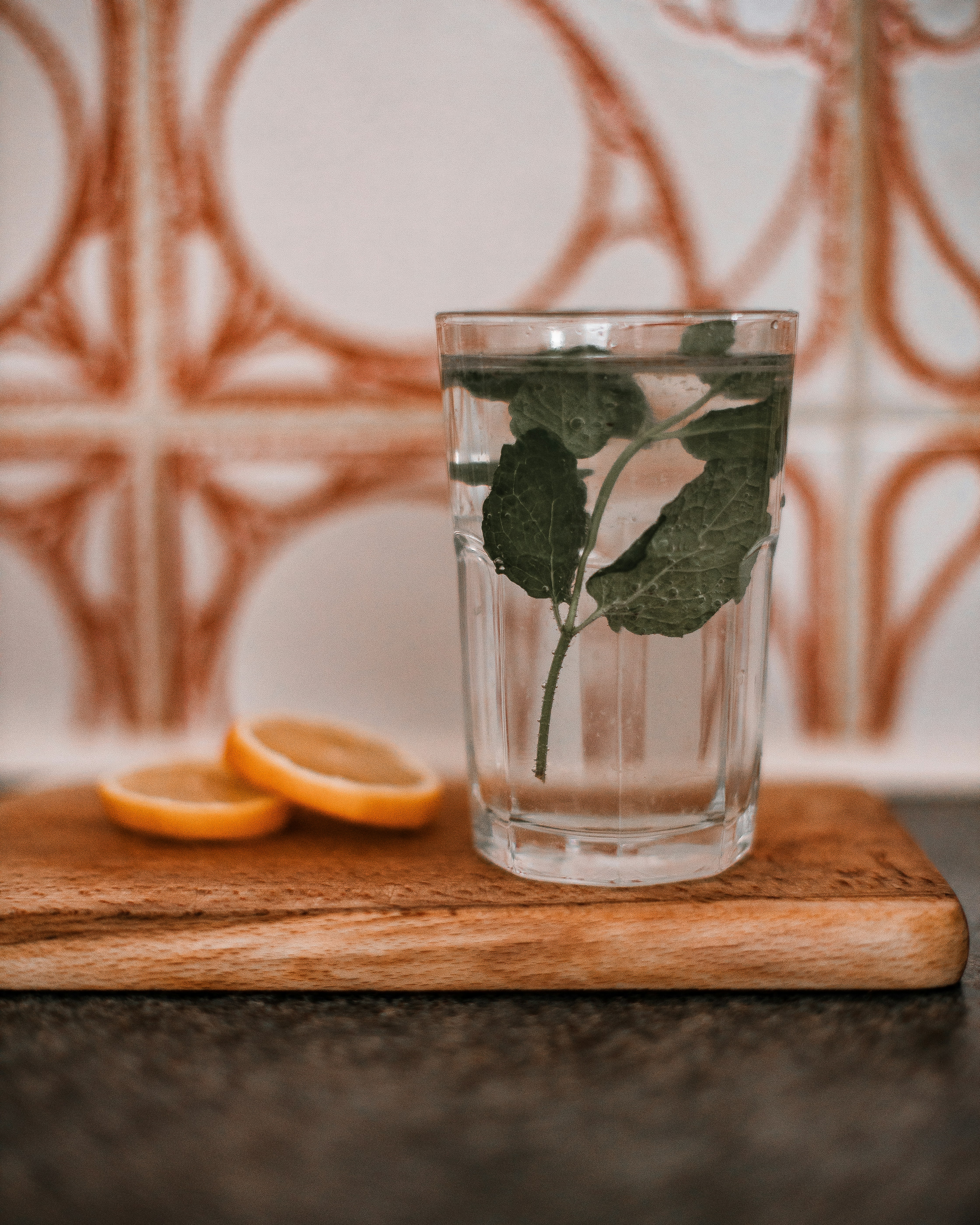 clear drinking glass with water and sliced lemon on brown wooden chopping board