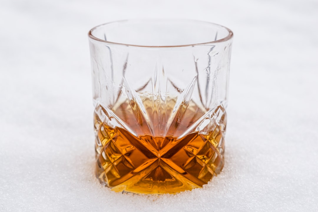clear drinking glass with brown liquid, Vintage crystal glass of bourbon whiskey in the snow.