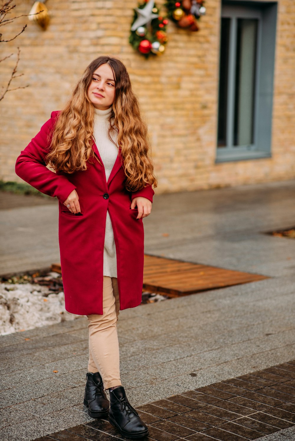 woman in red coat standing on gray concrete road during daytime