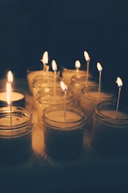 A cozy arrangement of softly glowing candles in glass jars with flickering flames casting warm light.