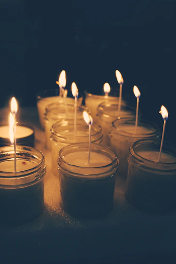 Cozy candle-lit workshop with people crafting candles together, surrounded by jars of colorful wax and flickering flames.