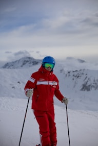 person in red jacket and helmet standing on snow covered ground during daytime
