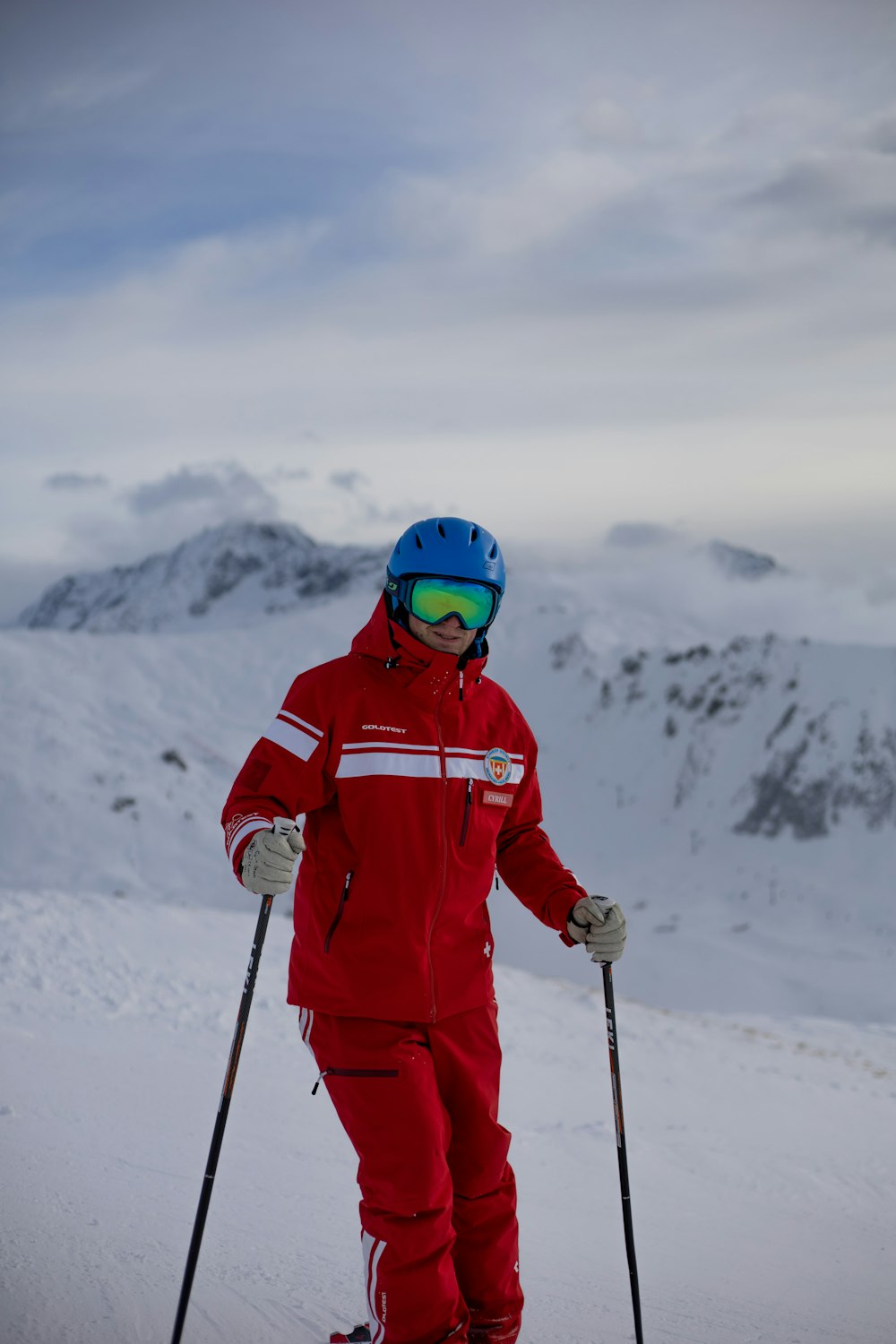 Person in roter Jacke und Helm, die tagsüber auf schneebedecktem Boden steht