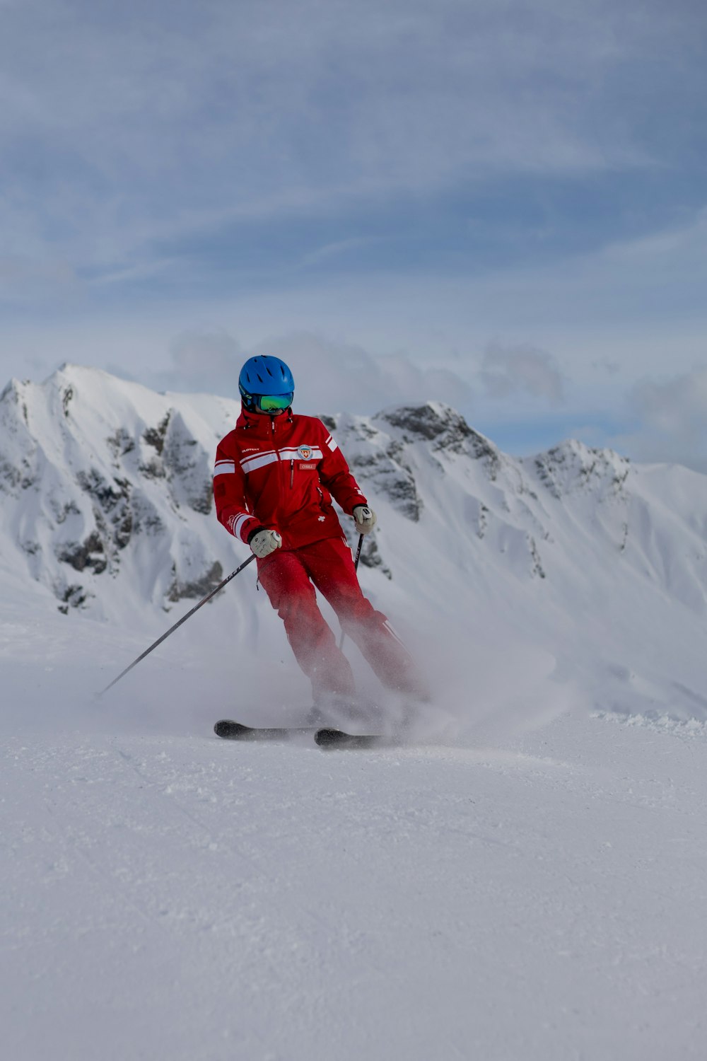Person in roter Jacke und blauem Helm, die tagsüber auf schneebedecktem Boden steht