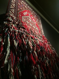 A close-up of a colorful handwoven tapestry hanging on a textured wall, showcasing intricate patterns and vibrant threads.