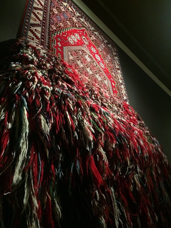 A close-up of a colorful handwoven tapestry hanging on a textured wall, showcasing intricate patterns and vibrant threads.