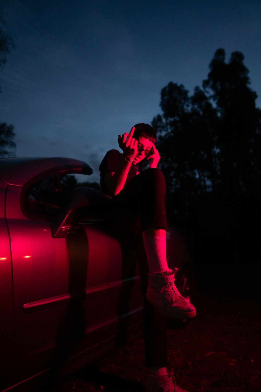 woman in black dress sitting on red car