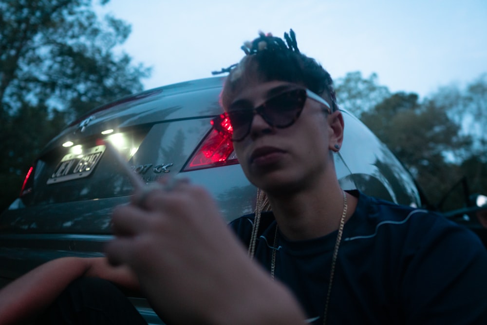 man in black sunglasses holding cigarette stick