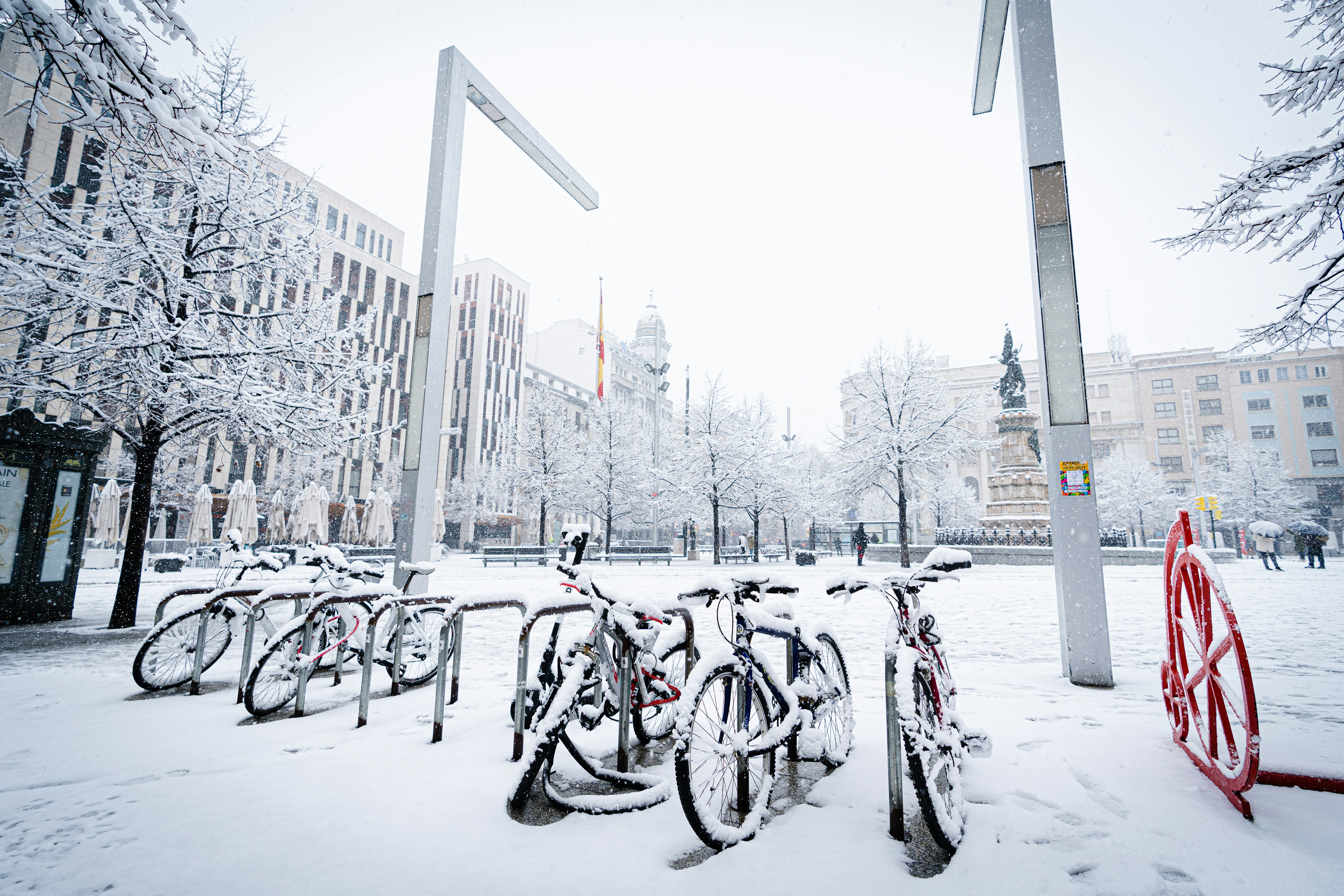 Bike station with bikes covered with snow.