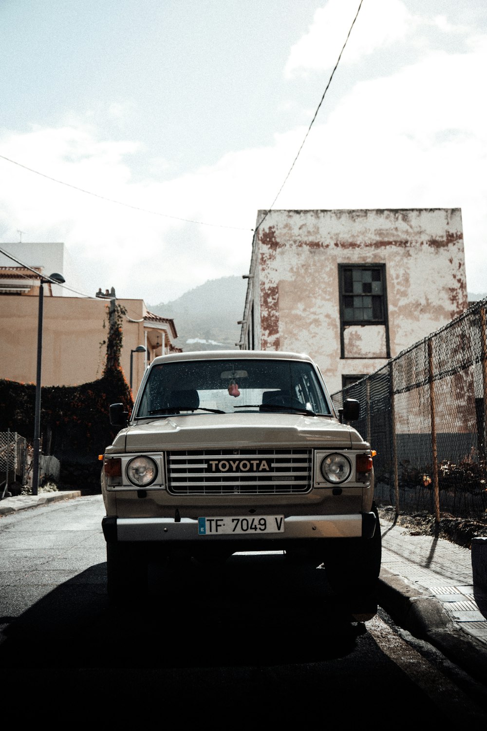 white ford car parked beside brown concrete building during daytime