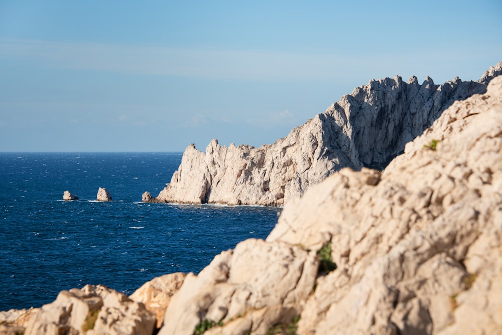 gray rocky mountain beside blue sea under blue sky during daytime