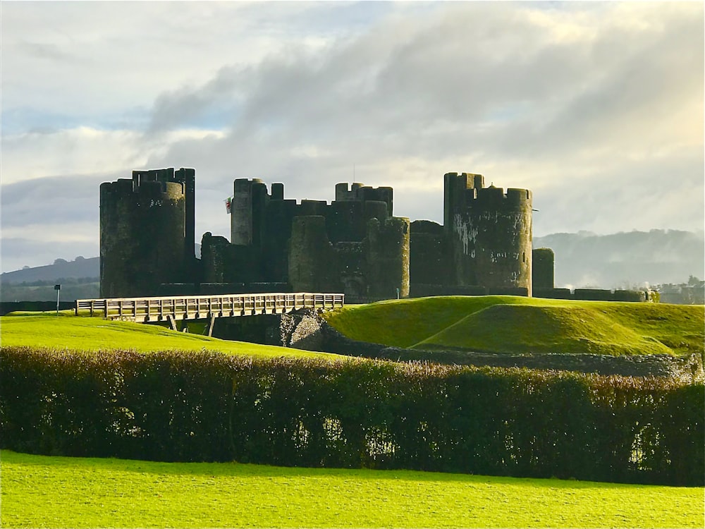 Campo de hierba verde cerca del castillo bajo nubes blancas durante el día