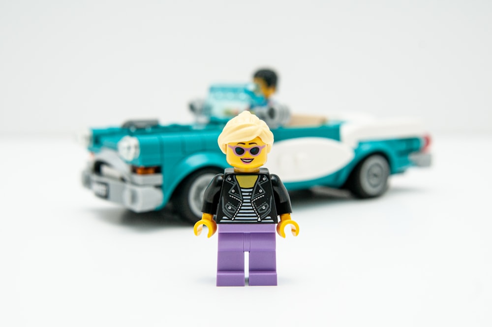 lego mini figure beside blue car