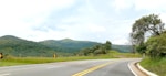 A winding country road surrounded by green hills and trees.