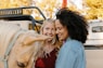 woman in blue denim jacket smiling beside woman in red shirt