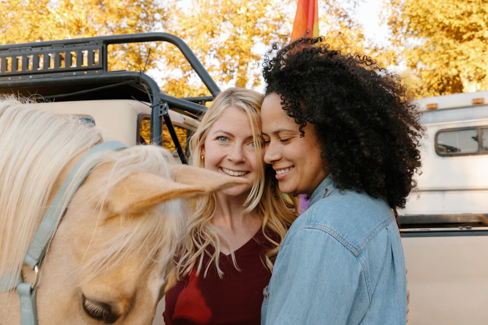 woman in blue denim jacket smiling beside woman in red shirt