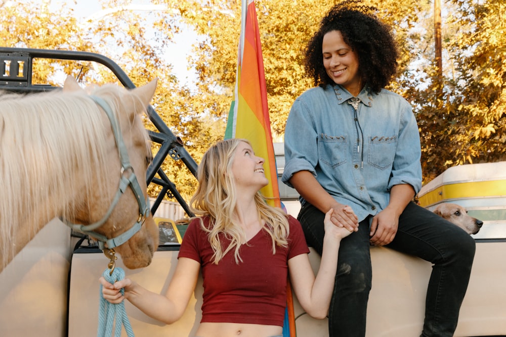 2 women sitting on black and brown horse