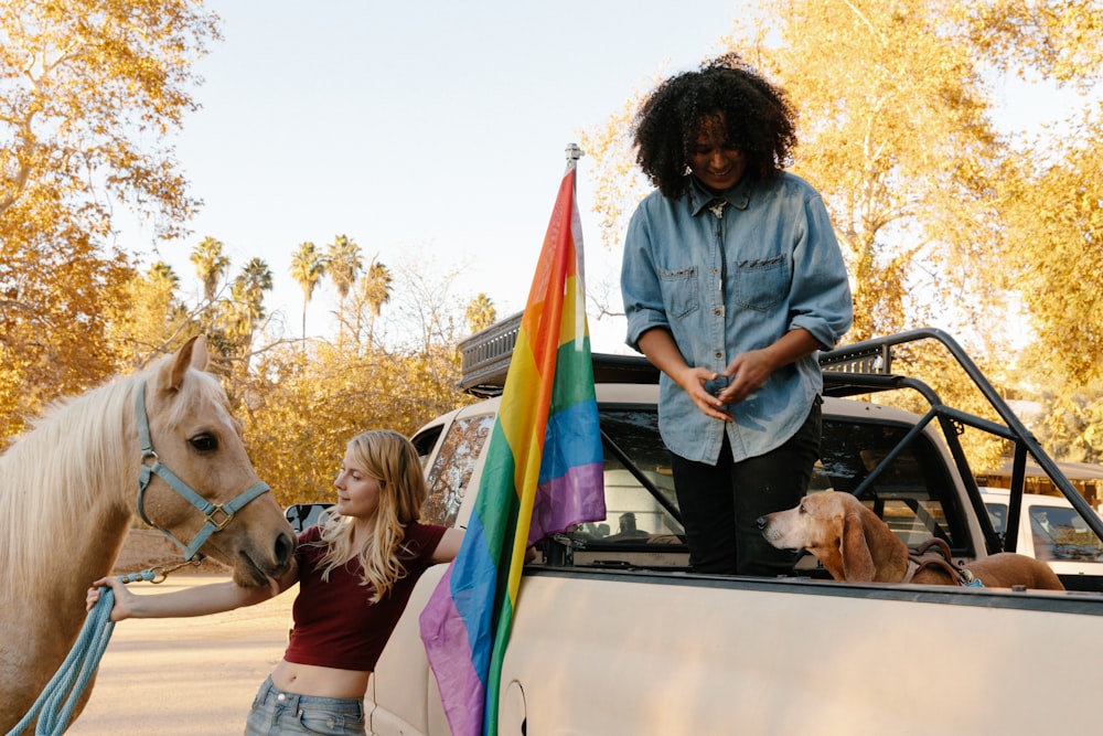 woman in blue denim jacket standing beside white horse during daytime