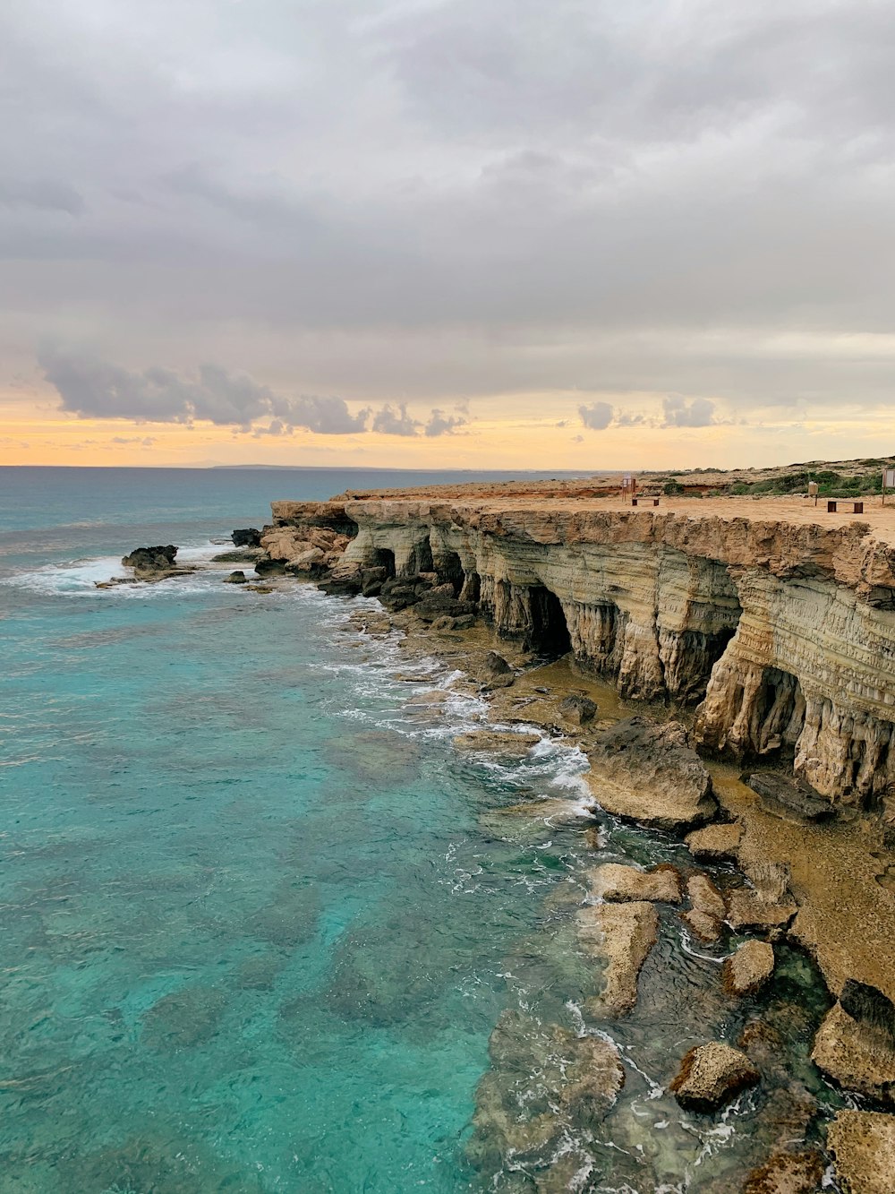 brown rocky mountain beside blue sea under white clouds during daytime