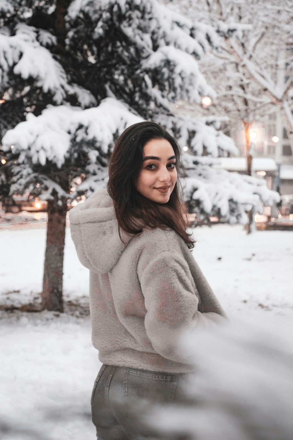 woman in gray sweater standing on snow covered ground during daytime