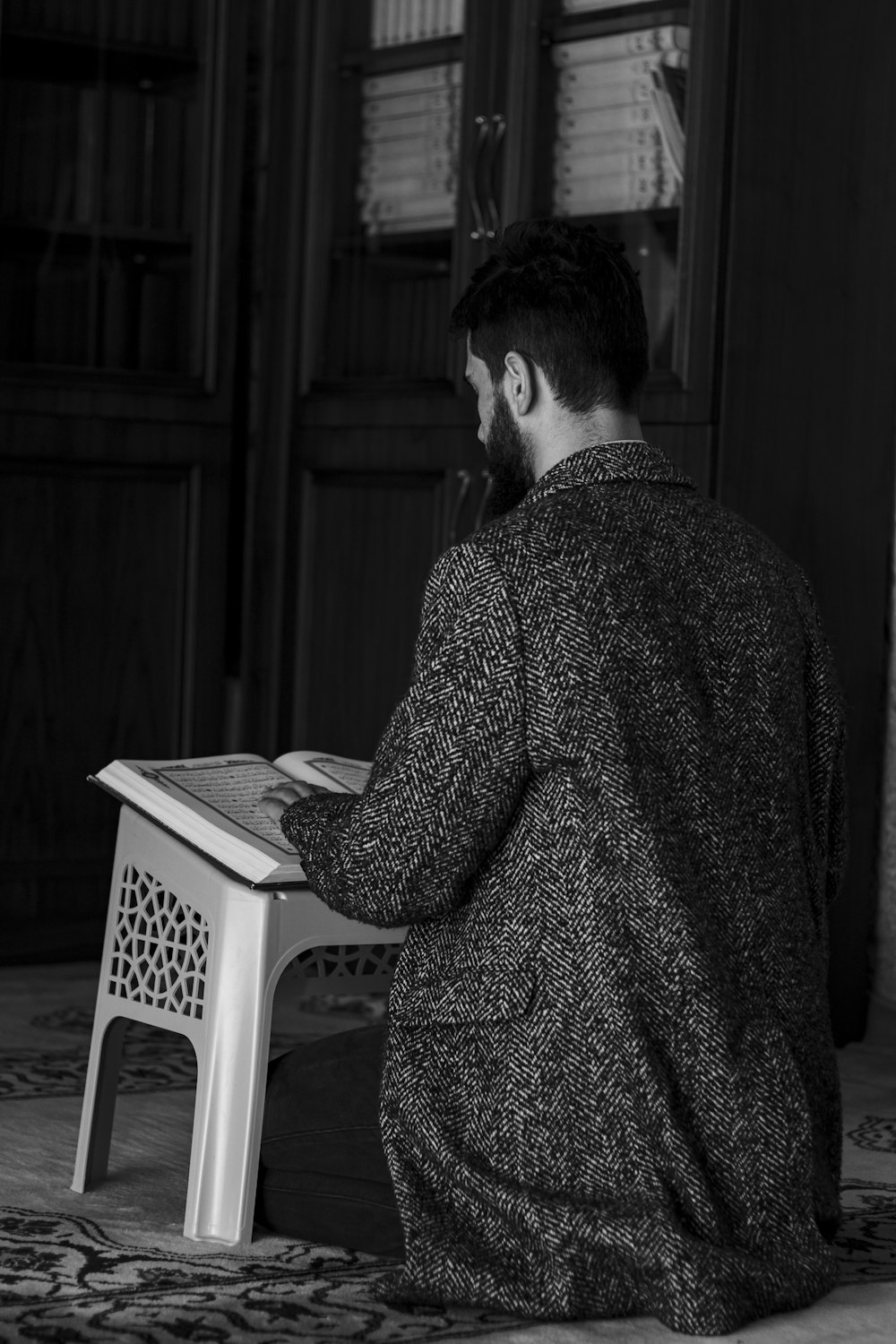 man in black and white checkered dress shirt standing near white plastic chair