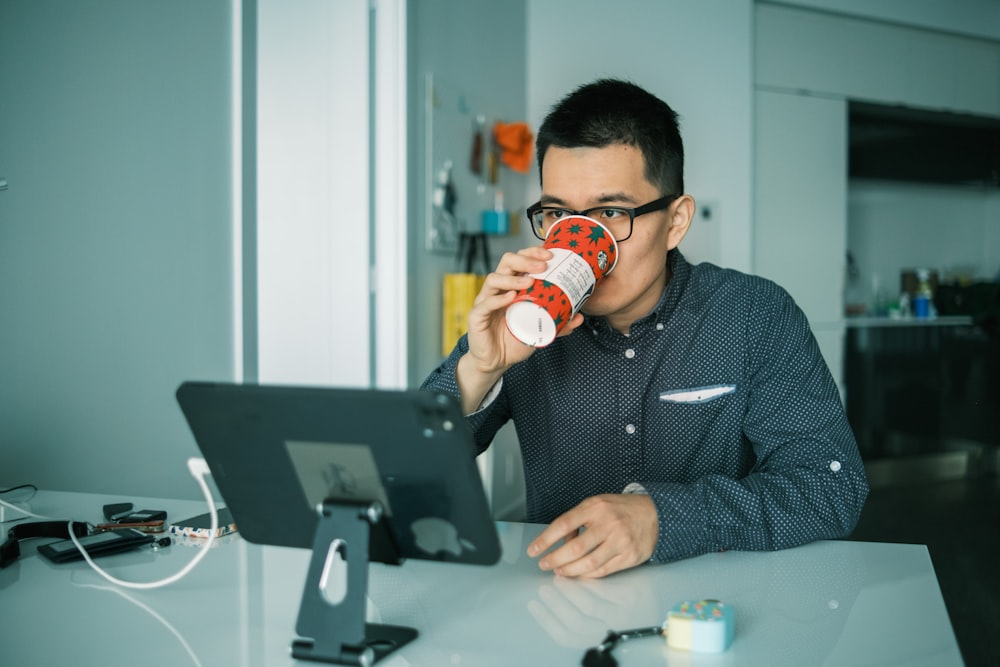 man in black and white checkered dress shirt drinking from brown and white ceramic mug