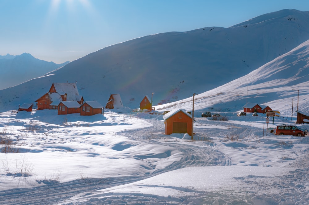 brown wooden houses on snow covered field during daytime