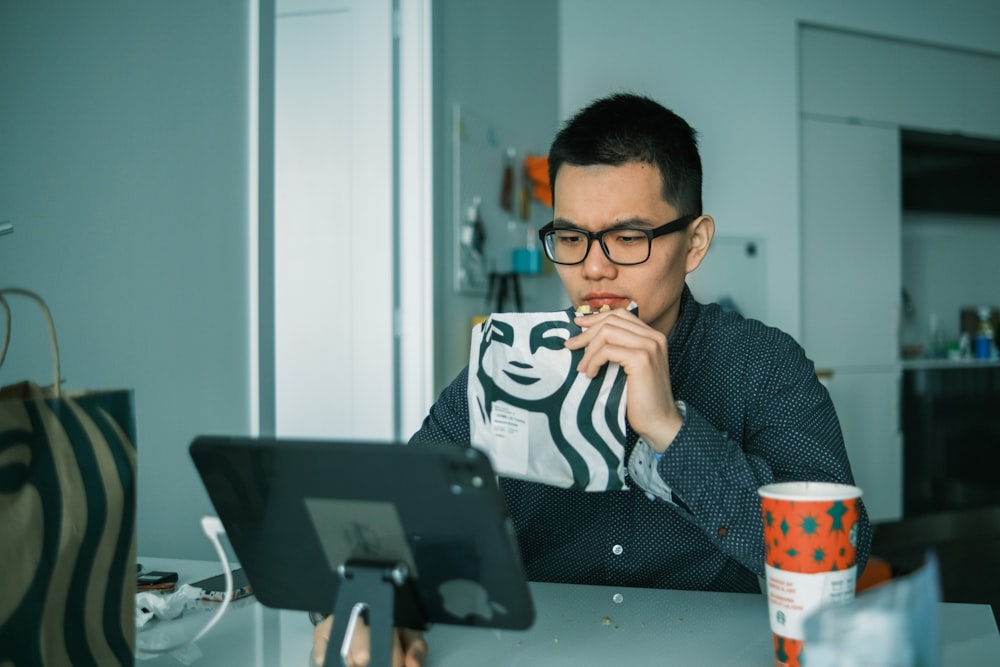 man in black and white sweater sitting beside black laptop computer