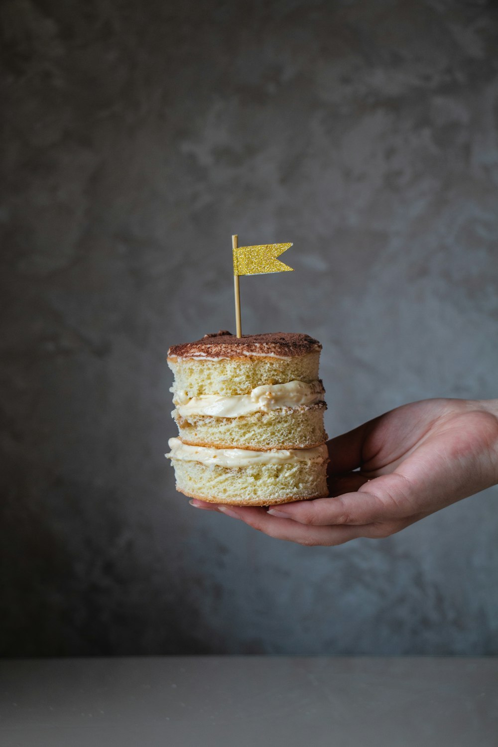 person holding brown cupcake with white icing