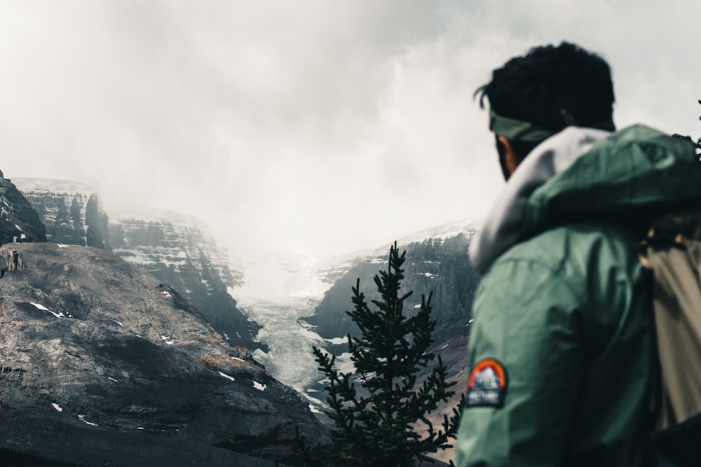 man in green jacket standing on rock formation during daytime