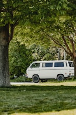 A sleek white van parked at Detling Aerodrome Estate surrounded by greenery on a sunny day.