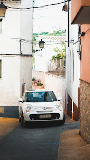 A compact car navigating through narrow, charming streets of an Italian village