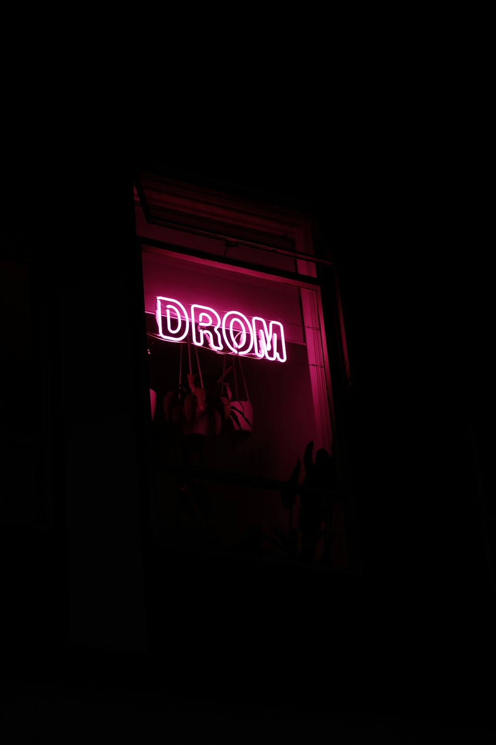 a neon sign that reads drom in a window