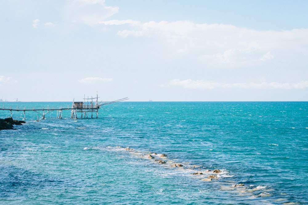 white and black wooden dock on blue sea under white clouds during daytime