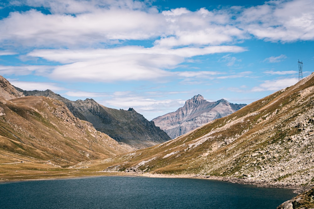 Braune und grüne Berge neben Gewässern unter blauem Himmel tagsüber