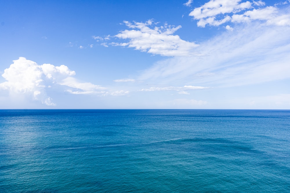 mar azul sob céu azul e nuvens brancas durante o dia