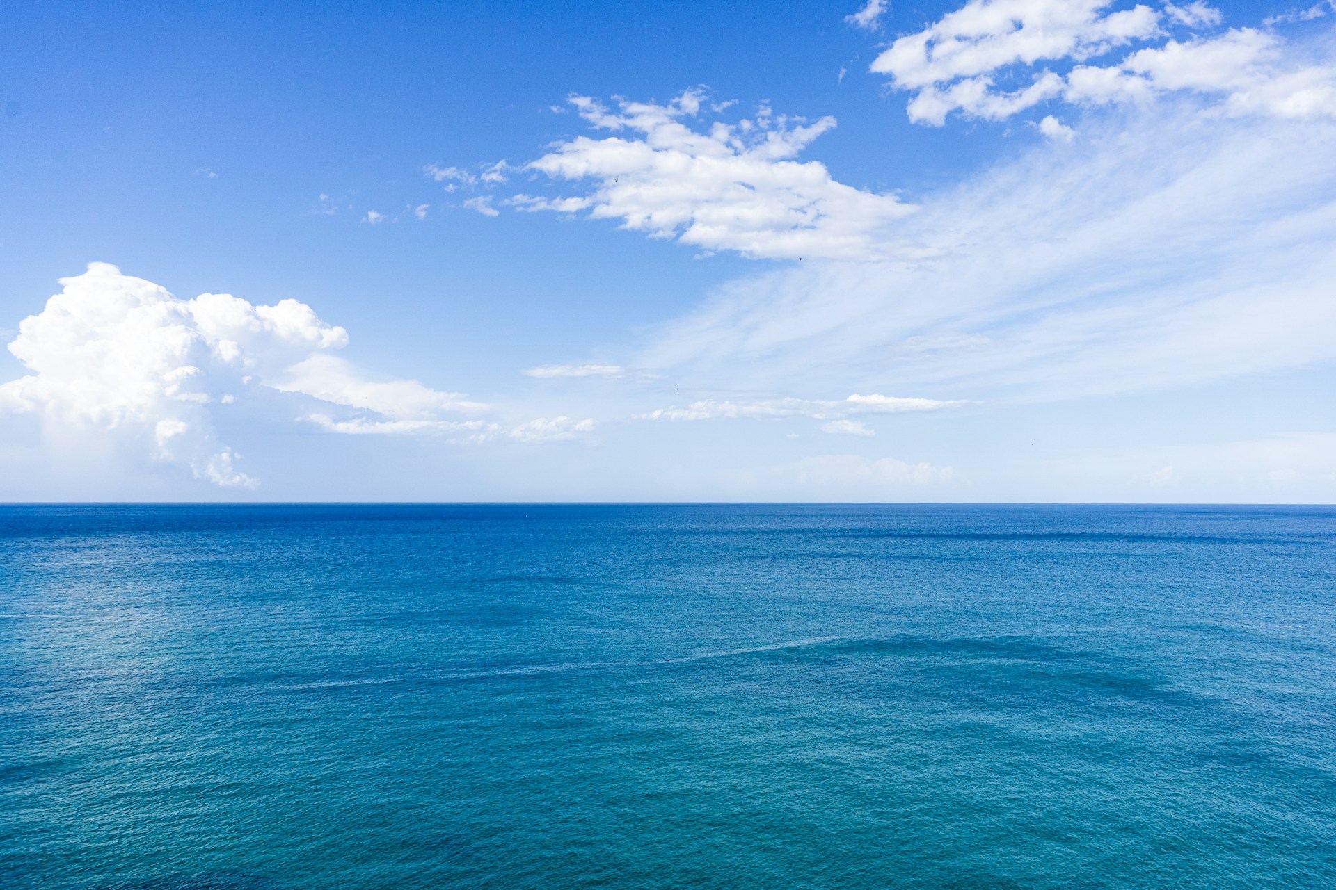 blue sea under blue sky and white clouds during daytime