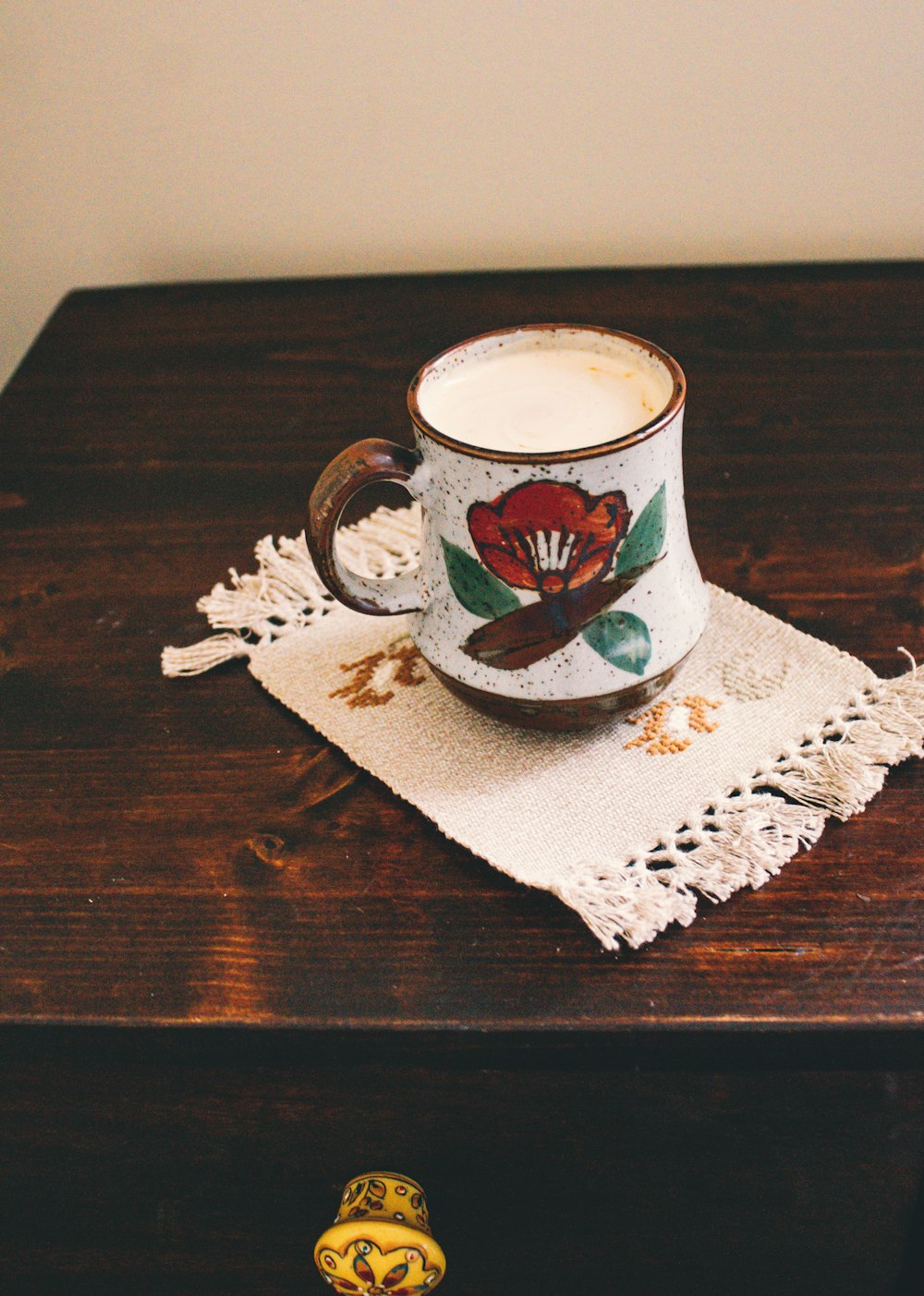 white green and red floral ceramic mug on white and brown floral textile