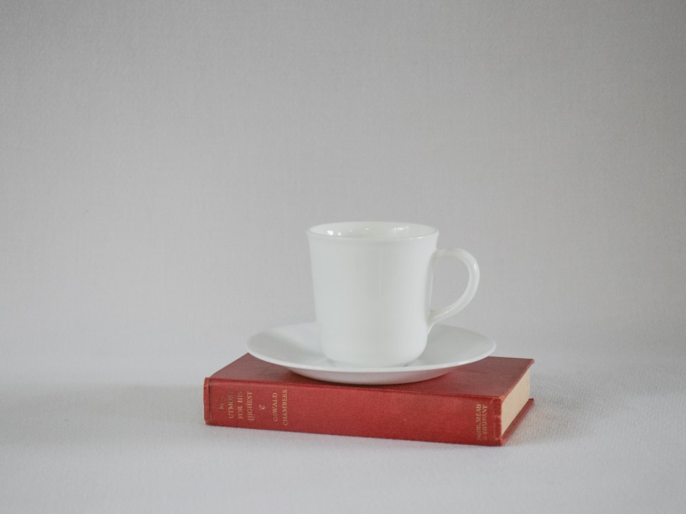 Taza de cerámica blanca en libro rojo
